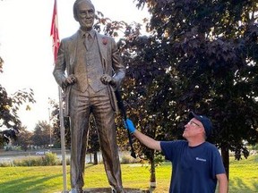 A worker removes spray paint from a statue of former Prime Minister Pierre Trudeau on Sunday, Aug. 16 2020