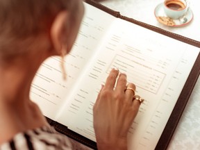 A woman reads the menu at a restaurant.