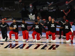 Coach Nick Nurse (left) and Raptors players kneel during the national anthem before Game 4 against the Nets in Lake Buena Vista, Fla. The Raps’ playoff run re-starts Sunday afternoon.