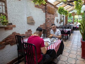 People eat food at Mamma Martino's Restaurant after indoor dining restaurants, gyms and cinemas re-open under Phase 3 rules restrictions in Toronto, Friday, July 31, 2020.