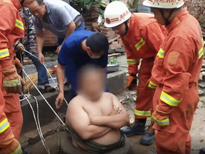 A large Chinese man, 28, identified only as Liu, gets stuck when he falls into his family's well in Fuliudian Village in Henan Province.