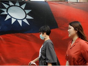 People walk past a Taiwanese flag amid the coronavirus disease (COVID-19) pandemic in Taipei, Taiwan, August 10, 2020.