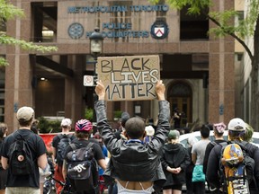 People protest the police in front of Toronto Police Service headquarters, in Toronto, Thursday, July 16, 2020.