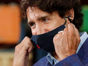 Canada's Prime Minister Justin Trudeau removes his face mask before speaking at the 3M's plant in Brockville, Ont. on Friday, Aug. 21, 2020.