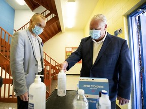 Ontario Premier Doug Ford, right, uses hand sanitizer as he gets a tour of Kensington Community School in Toronto from principal Dan Fisher on Sept. 1, 2020.
