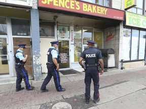 Toronto Police and special constables walk past a restaurant in Little Jamaica were six people were wounded in a shooting Tuesday.