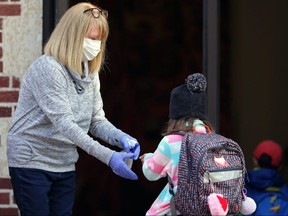 Staff spray hand sanitizer at the entrance to Grosvenor School on the first day back in Winnipeg on Tues., Sept. 8, 2020.