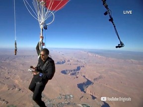 Extreme performer David Blaine hangs with a parachute under a cluster of balloons during a stunt to fly thousands of feet into the air in a still image from video taken over Page, Arizona, U.S. September 2, 2020.