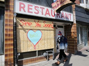 A man wearing a protective mask passes a boarded up restaurant in Toronto April 6, 2020.