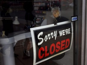 A closed sign is seen in the window of a small business.