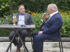 Ontario Premier Doug Ford, right, sits with Quebec Premier Francois Legault as they drink beer during a photo opportunity ahead of the Ontario-Quebec Summit, in Toronto, Tuesday, Sept. 8, 2020.