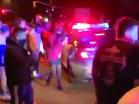 People kick squad cars and gave police the finger at a 'Toronto Takeover' event near the Toronto Zoo early Saturday, Sept. 12, 2020.