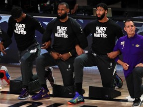LeBron James of the Los Angeles Lakers, along with temmate Anthony Davis, kneels during the national anthem at AdventHealth Arena at the ESPN Wide World Of Sports Complex on September 4, 2020 in Lake Buena Vista, Florida.
