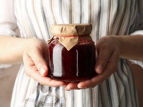 Woman holds glass jar with strawberry jam.