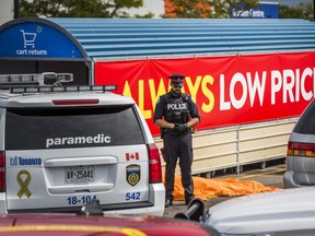 A Toronto Police officer stands by the body of a man shot dead in the Walmart parking lot on St. Clair Ave. W. near Runnymede Rd. in Toronto, Ont. on Sept. 10, 2020.