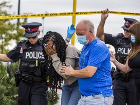 A distraught woman is comforted as Toronto Police are at the scene after a man was found dead in the Walmart parking lot on St. Clair Ave. W. near Runnymede Rd. in Toronto on September 10, 2020.  The unidentified woman was sitting on the ground against a police car behind the police tape.