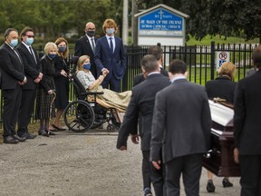 Loretta Traynor (on wheelchair), hold hands with her son Samuel,  while watching  the bringing in of one of four caskets for the funeral mass for her husband - Christopher Traynor, and their children - Bradley, 20, Adelaide 15 and Joseph, 11 at St. Mary of the People Catholic Church in Oshawa, Ont.  on Thursday September 17, 2020.