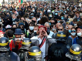 A man shouts slogans as he stands facing French riot police during a demonstration called by the "yellow vest" (Gilets Jaunes) movement in Paris, Saturday, Sept. 12, 2020.