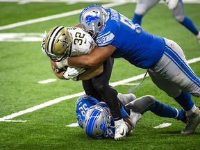 Michael Burton of the New Orleans Saints is tackled by a pair of Lions.