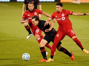 Toronto FC midfielder Nick DeLeon gets tangled up with New York Red Bulls defender Kyle Duncan.