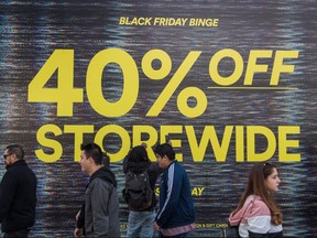 In this file photo taken on November 29, 2019, shoppers walk past a store promotion during the Black Friday sales in Los Angeles, California. - US retail spending was unexpectedly sluggish in November as consumers held back at the start of the holiday shopping period, according to a government report on December 13, 2019. Shoppers tightened their purse strings at bars, restaurants and department stores while buying less clothing and fewer sporting goods, according to the Commerce Department's monthly data.