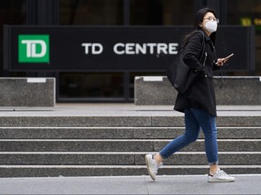 A woman in a mask walks in the financial district in Toronto, Ontario on March 24, 2020. - The province of Ontario has set a deadline of midnight Tuesday for all non-essential businesses to close due to the Covid-19 outbreak.