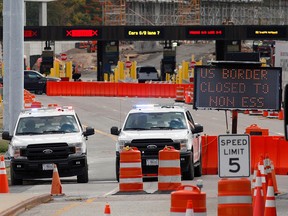 U.S. customs vehicles stand near a sign reading that the border is closed to non-essential traffic, at the Canada-United States border crossing at the Thousand Islands Bridge in Lansdowne, Ont. On September 28, 2020.