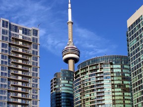 CN Tower and residential buildings against blue sky, Toronto, Ontario, Canada.