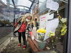 Nancy Bokma places a candle during a gathering of residents following the death of homeless person Michael Kent, who lived in this bus shelter along The Esplanade in Toronto, Ont. on Wednesday October 28, 2020.
