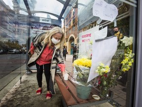 Nancy Bokma places a candle during a gathering of residents following the death of homeless person Michael Kent, who lived in this bus shelter along The Esplanade in Toronto, Ont. on Wednesday, Oct. 28, 2020.