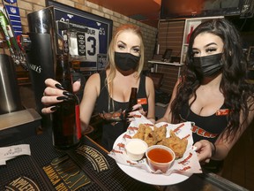 Erin (L) and Ryleigh - staff at the Hooters restaurant at Adelaide St. West and John St. serve up beer and wings before the new midnight deadline shutting them down for inside dining for the next 28 days because of newly implement COVID restrictions on Friday October 9, 2020. Jack Boland/Toronto Sun/Postmedia Network