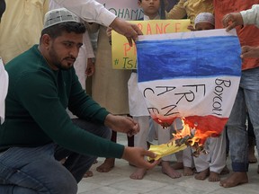 Muslim devotees burn a French flag during a demonstration to protest against French President Emmanuel Macron comments over Prophet Mohammed cartoons, in Amritsar on October 30, 2020.
