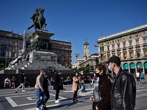 People wearing protective masks walk across the Piazza del Duomo in Milan on Saturday, Oct. 17, 2020.