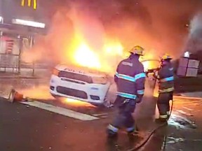 Firefighters hose down a burning police vehicle during protests after the death of Walter Wallace Jr., a Black man who was shot by police in Philadelphia, October 27, 2020 in this still image taken from social media video.