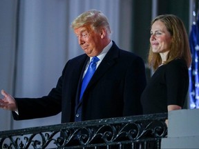 U.S. President Donald Trump gestures as he poses with U.S. Supreme Court Associate Justice Amy Coney Barrett on a White House balcony after she was sworn in to serve as an associate justice of the U.S. Supreme Court at the White House in Washington, D.C., Monday, Oct. 26, 2020.