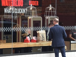 Prince William, Duke of Cambridge speaks to a member of the public through the window of a KFC restaurant before attending the launch of the Hold Still campaign at Waterloo Station.