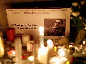 Candles are lit at a makeshift memorial as people gather to pay homage to Samuel Paty, the French teacher who was beheaded on the streets of the Paris suburb of Conflans-Sainte-Honorine, as part of a national tribute, in Nice, France, October 21, 2020.