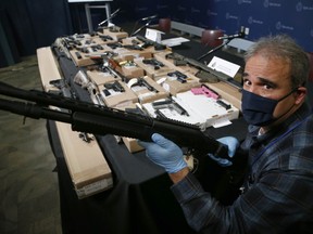 Special Const. Ed Costa with some of the 31 firearms seized during a multi-jurisdictional police investigation -- dubbed Project Sunder -- that targeted the Eglinton West Crips street gang at Toronto Police Headquarters on Thursday, Oct. 29, 2020.