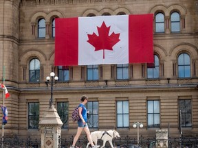 A woman walks past the the Office of the Prime Minister and Privy Council building in the parliamentary precinct in downtown Ottawa, Tuesday, June, 30, 2020.