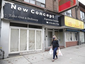 A single pedestrian walks by empty businesses on Queen St E., near Wheeler Ave. in the Beaches, on Thursday, Oct. 22, 2020.