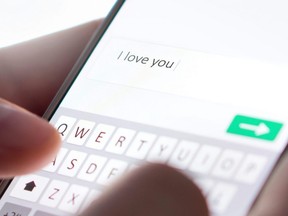 Sending an "I love you" text message with a cell phone.
