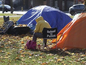 A person sits by two tents in Alexandra Park, at Bathurst and Dundas Sts., on Nov. 10, 2020.
