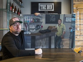 Cabbagetown pub owner Regan Irvine holds a painting of his father at his closed bar, The Irv, on Nov. 23, 2020.