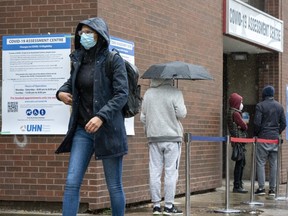 A man walks past the lineup for Covid19 Assessments at Toronto Western Hospital in Toronto on Oct. 27, 2020.