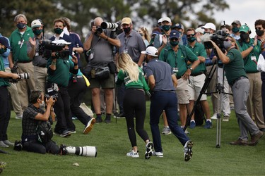 Dustin Johnson of the U.S. celebrates with partner Paulina Gretzky as they walk off the 18th green after winning The Masters.