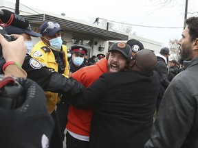 Adamson BBQ owner Adam Skelly is led away from his restaurant by Toronto Police as supporters tried to wrestle him away on Thursday, November 26, 2020.