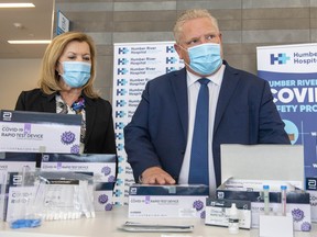 Ontario Premier Doug Ford and Health Minister Christine Elliott listen as they are briefed on Covid-19 Rapid Test Device kits at Humber River Hospital in Toronto on Nov. 24, 2020.