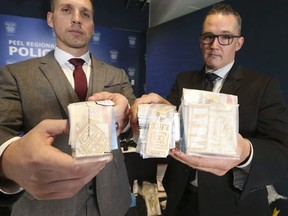 Peel Regional Police Det.-Sgts. Chad Lines (L) and Derek Meeker hold up seized jewelry sporting the name of the gang, New Money Suh Sick