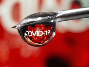 The word "COVID-19" is reflected in a drop on a syringe needle in this illustration taken November 9, 2020. REUTERS/Dado Ruvic/Illustration
