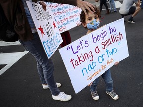 A kid wearing a face mask holds a sign at Black Lives Matter Plaza near the White House after Election Day in Washington, D.C. November 6, 2020.